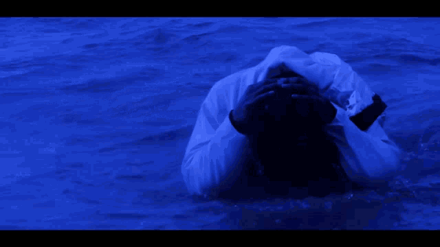 a person standing in a body of water with a blue background