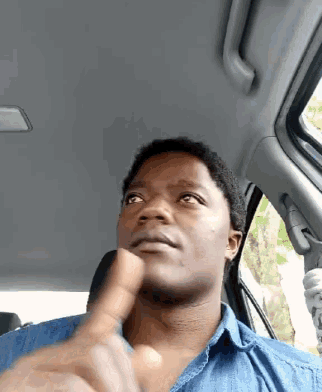 a man in a denim shirt is giving a thumbs up
