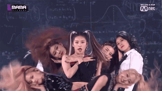 a group of women are posing for a photo in front of a blackboard with mathematical equations on it