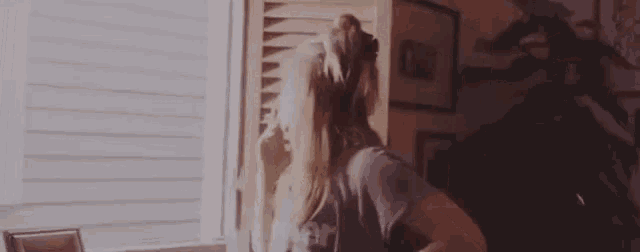 a woman is standing in front of a window with her arms outstretched in a living room .