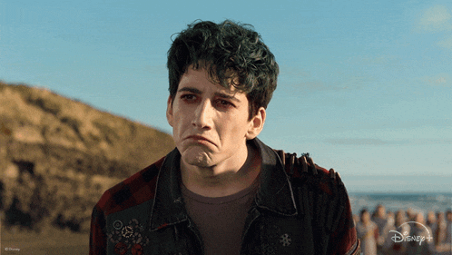 a man with green hair is wearing a plaid shirt and a disney + jacket