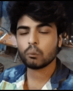 a young man with a beard is making a funny face with his eyes closed .