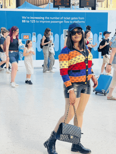a woman walking in front of a sign that says " we 're increasing the number of ticket gates "