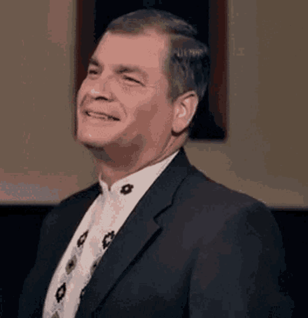 a man in a suit and tie is smiling and laughing .