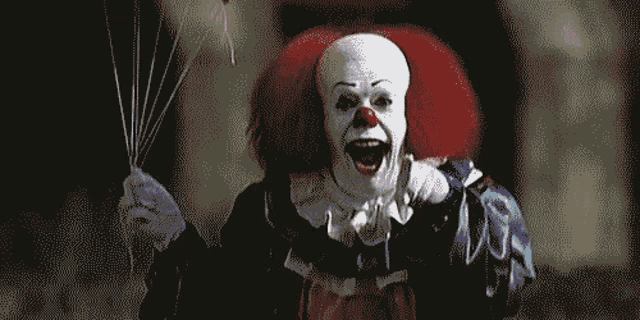 a clown is holding a bunch of balloons in his hand