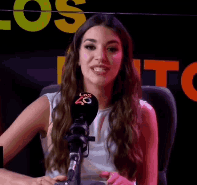 a woman sitting in front of a microphone with los 40 on it