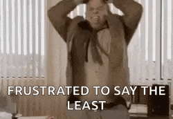 a man is standing in front of a window with his hands on his head and the words `` frustrated to say the least '' .