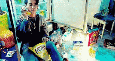 a man is sitting on the floor with a bag of lays chips on his lap .