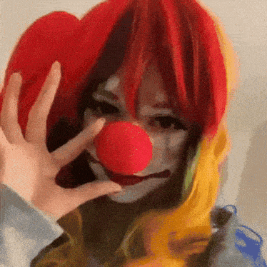 a woman is dressed as a clown and holding a red nose .