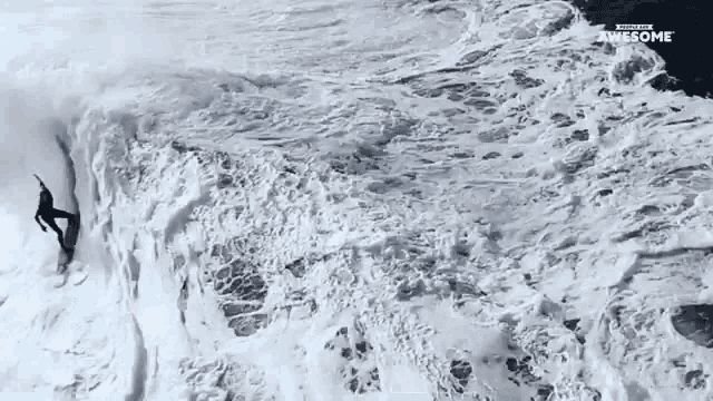an aerial view of a surfer riding a wave with the words " awesome " on the bottom left