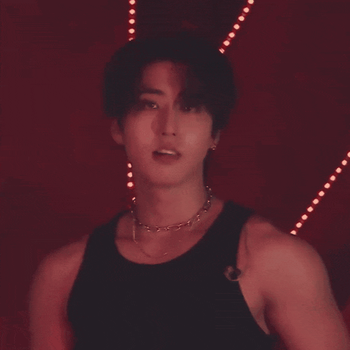 a close up of a man wearing a black tank top and a necklace