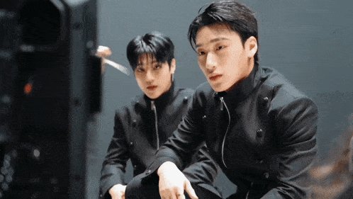 two boys in black jackets are sitting next to each other