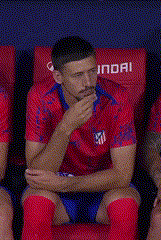 a soccer player is sitting in a locker room with his hands folded and his mouth open .
