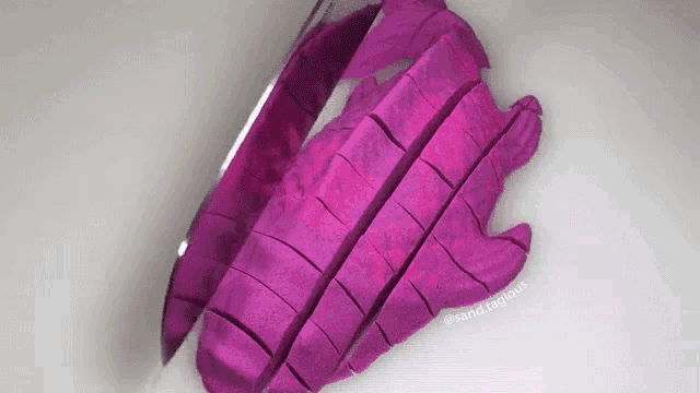 a purple vegetable is being cut into pieces with a knife on a cutting board .