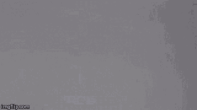 a close up of a person standing in a room with smoke coming out of their mouth .