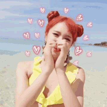 a woman in a yellow bikini is making a heart with her hands