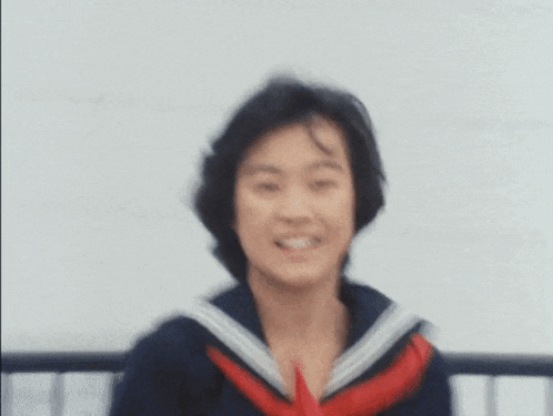 a blurry picture of a woman in a school uniform smiling .
