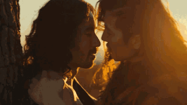 a man and woman kissing in front of a tree