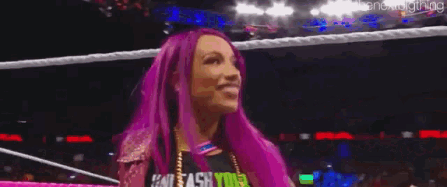 a woman with purple hair is standing in a ring with her tongue out .