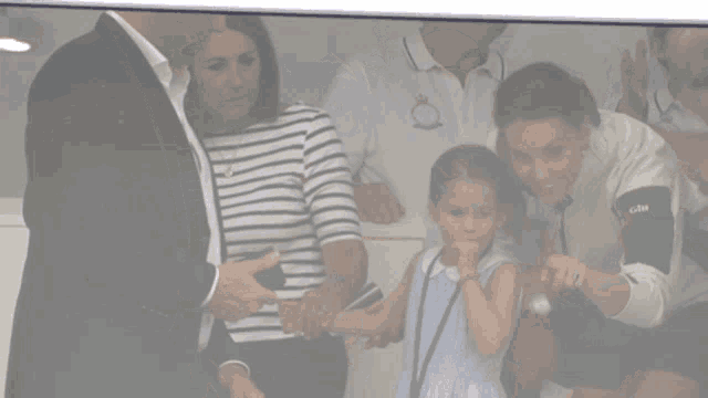a woman wearing a gill shirt holds a little girl 's arm