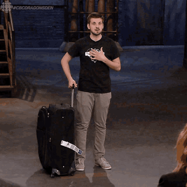 a man wearing a black shirt that says skyscraper is pushing a suitcase
