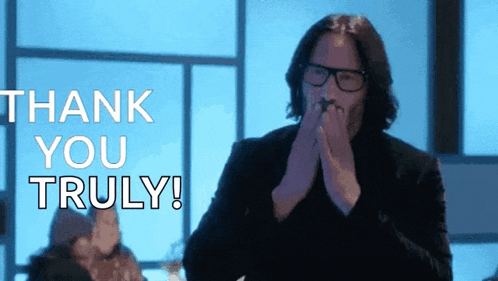 a man wearing glasses is clapping his hands in front of a thank you truly message