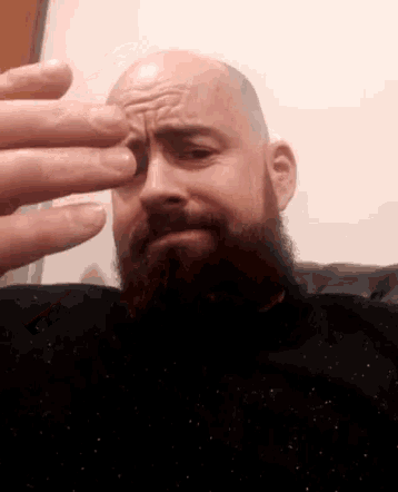 a bald man with a beard is making a face with his hands