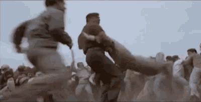 a group of people are running in a field while a man is kicking a pig .