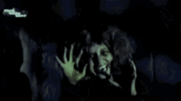 a close up of a person 's face with a green hand reaching out .