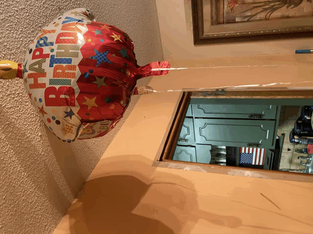 a red and white happy birthday balloon is hanging from a string