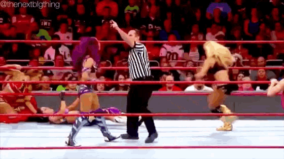 a referee is standing in the middle of a wrestling ring while a wrestler falls on the ground .
