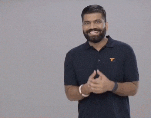 a man with a beard is wearing a black shirt with the letter t on the front