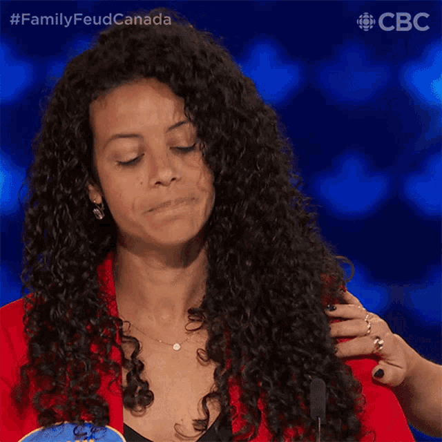a woman with curly hair is wearing a red jacket and a blue name tag that says sally