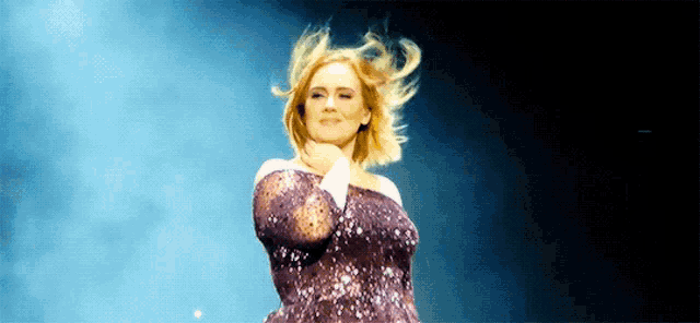 a woman in a purple dress is dancing on stage .