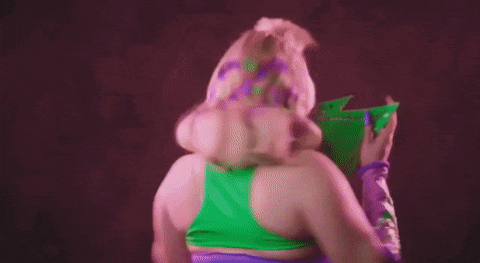 a woman in a green top and purple gloves is holding a green bag of chips .