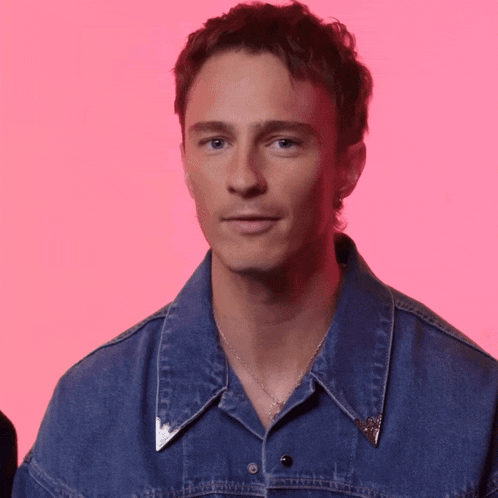 a young man wearing a denim shirt and a necklace
