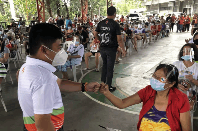 a man wearing a ccps jersey shakes hands with a woman wearing a mask
