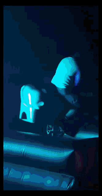 a man in a blue shirt is riding a bull in the dark