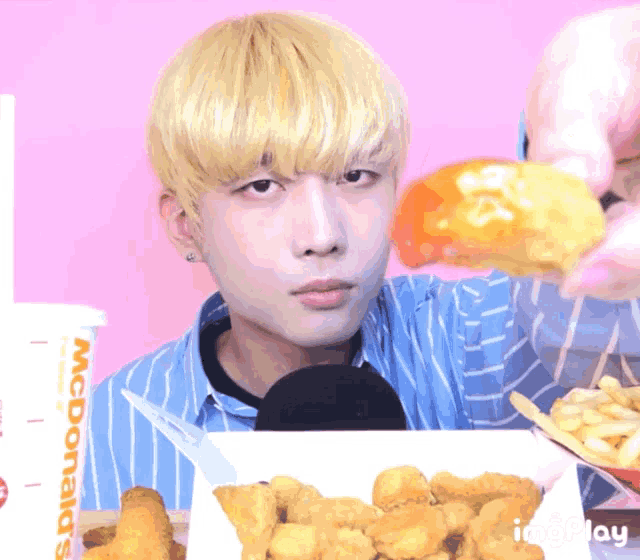 a man eating chicken nuggets next to a mcdonald 's cup