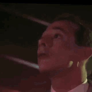 a man in a suit is dancing in front of a neon sign that says bud light