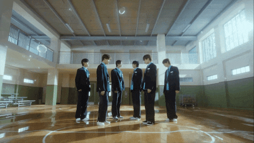 a group of young men are standing in a circle in a gym