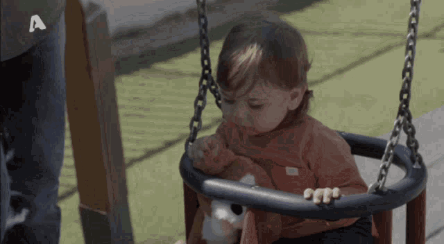 a baby is sitting on a swing with the letter a on the bottom right