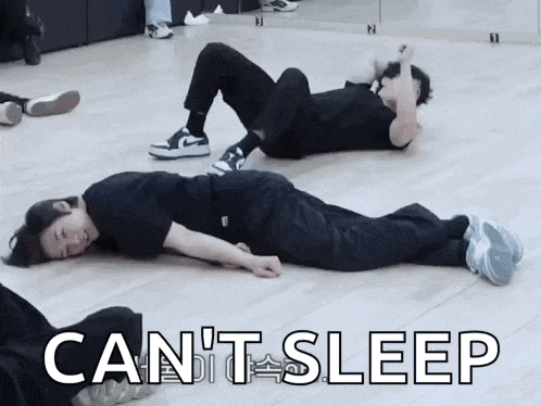 two men are laying on their stomachs on the floor in a dance studio .