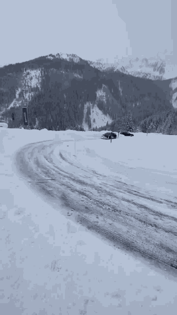 a car is driving through the snow on a snowy road .