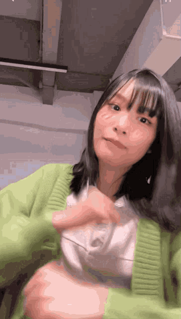 the girl is wearing a green sweater and white shirt