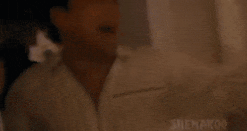 a man in a white shirt is standing in front of a mirror in a room .