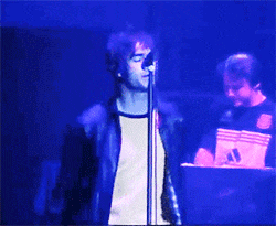 a man singing into a microphone with the word adidas on his shirt