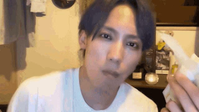 a man with purple hair is eating a piece of paper