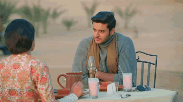 a man and a woman are sitting at a table with pink drinks
