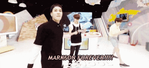 a man in a black shirt is standing in front of a sign that says " markson forever "